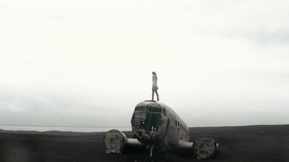 Young Woman Standing on the Top of Breaker DC3 Plane in Iceland, Female Exploring Deserted Black