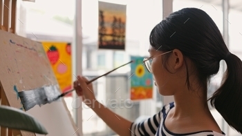 A girl is painting a picture on a canvas