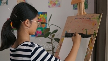 A girl is painting a picture on a canvas