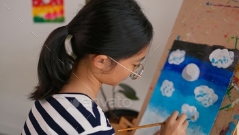 A girl is painting a picture on a canvas