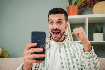 Young man celebrating that he has won a sports bet while checking the result on a smartphone app. A