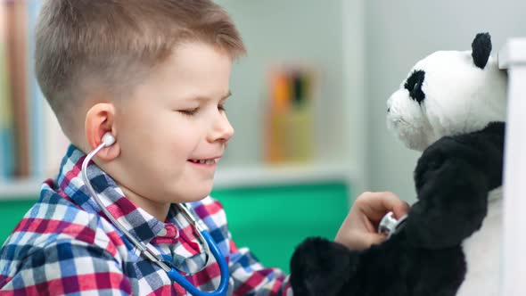 Adorable Boy is Using a Stethoscope While Playing a Doctor with His Soft Toy