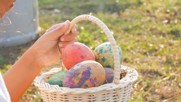 Close-up of children hand holding a basket with Easter eggs in sunshine