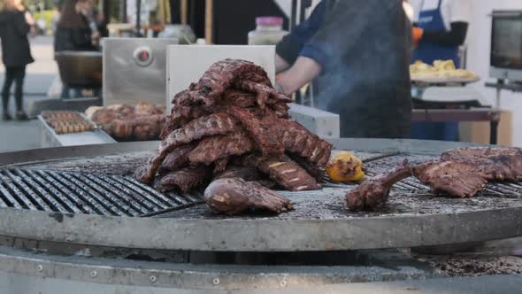 Large Cuts of Beef Are Cooked on Rotating Outdoor Grill at Street Food Festival