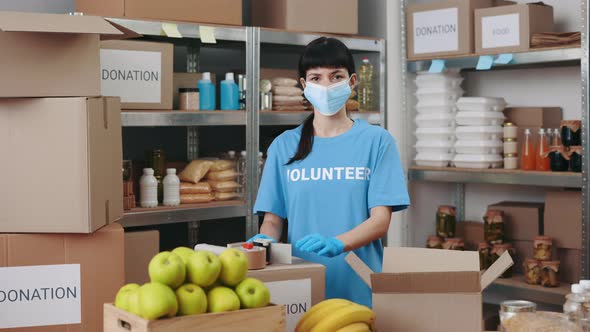 Female Volunteer in Face Mask and Gloves Posing at Food Bank