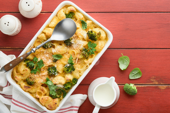 Casserole Mac and cheese. Baked Mac and cheese with broccoli, cream sauce and parmesan on red old ru