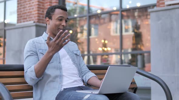 Online Video Chat on Laptop By African Man Sitting on Bench