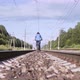 Woman Rides Away a Bicycle on Railway Sleepers in Summer Day at Countryside - VideoHive Item for Sale