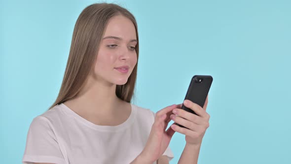 Happy Young Woman Celebrating Success on Smartphone , Blue Background