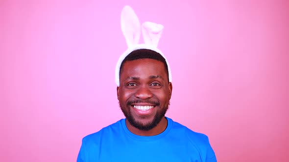 Man Wearing Cute Easter Bunny Ears in Studio Pink Wall Background