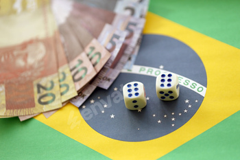 Dice cubes with brazilian money bills on flag of Brasil Republic