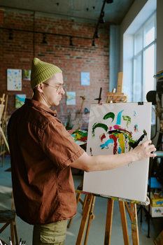 Young Male Artist Painting On Canvas