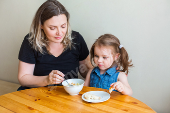 Woman feeding girl in kitchen