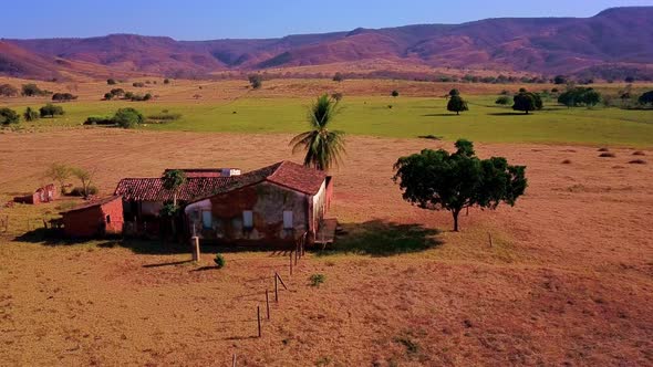 Slow aerial drone shot flying over an old abandoned house in the middle of rural barren Bahia