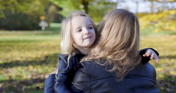 Mother and child daughter hugging and embracing at park