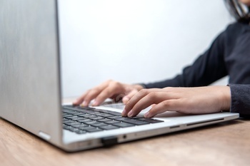 Hands typing on a laptop keyboard.