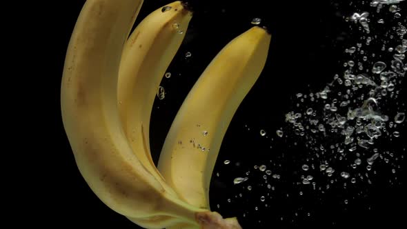 Slow Motion Bananas Falling Into Transparent Water on Black Background