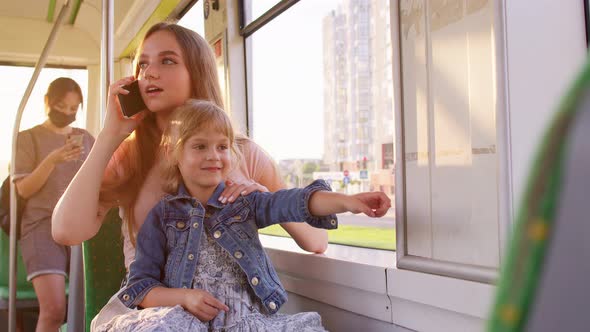 Young Family Woman with Kid Girl Sitting in Public Bus Transport Mother Talking on Mobile Phone