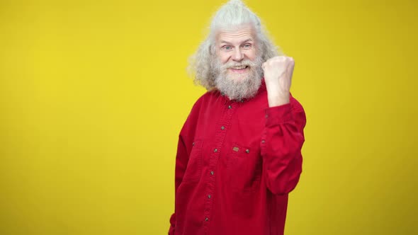 Happy Excited Senior Man Showing Yes Gesture and Smiling on Yellow Background