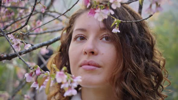 Closeup Portrait of Pretty Girl in Park with Blooming Japanese Sakura Trees