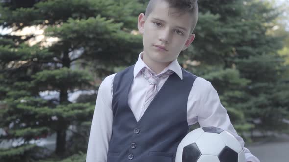 Portrait Cute Well-dressed Boy Standing on the Street Holding the Soccer Ball and Purse