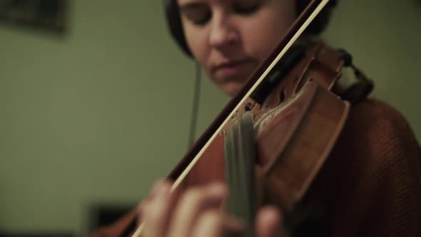 Female Artist Rehearsing the Instrumental Melody with Violin Using Headphones