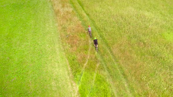 Aerial view of man and woman cycling on dirt road in the summertime.