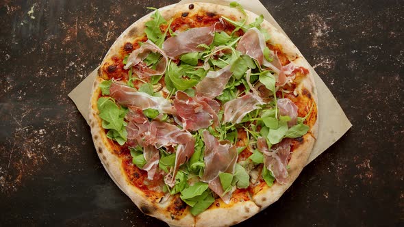 Delicious Pizza with Prosciutto Parma Ham, Arugula Salad Rocket on Rusty Dark