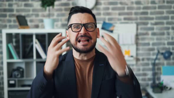 Portrait of Angry Bearded Guy Shouting and Pointing at Camera in Office