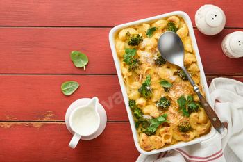 Casserole Mac and cheese. Baked Mac and cheese with broccoli, cream sauce and parmesan on red old ru