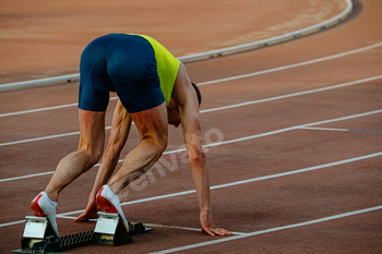 male runner in starting blocks sprint race