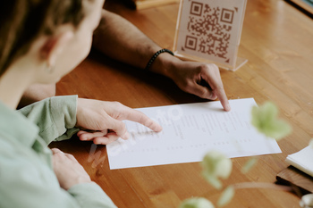 Reading Restaurant Menu with QR Code on Wooden Table