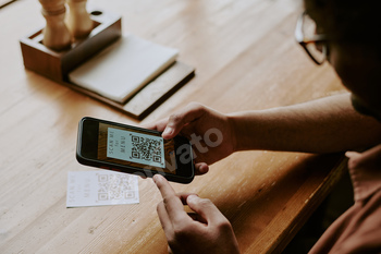 Scanning QR Code with Smartphone Device on Wooden Table