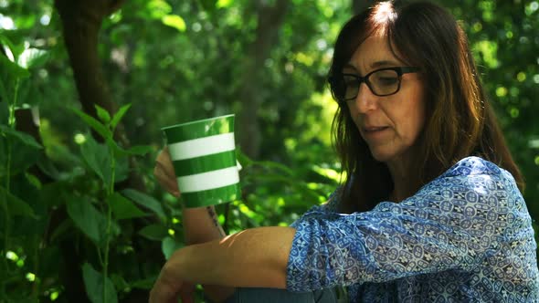 Mature woman having coffee in the garden