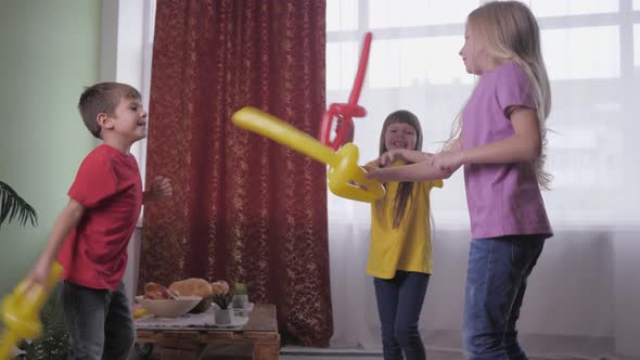 Smiling Friends Girls Actively Fight with Boy in Balloons During Children Party Celebration