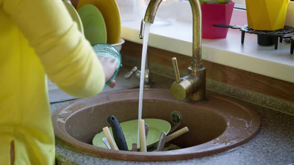 Housewife Washes a Dirty Glass Cup in the Sink with a Sponge with Detergent.