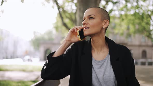 Laughing bald woman talking by phone and looking around