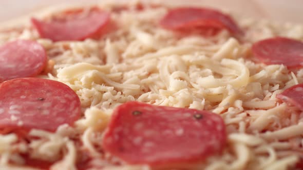 Camera follows putting pepperoni on a pizza dough. Slow Motion.