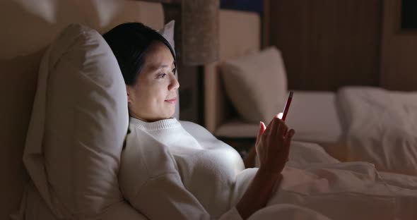 Woman watch on cellphone on bed