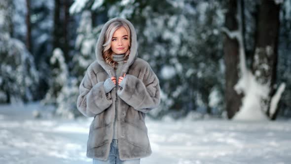 Gorgeous Young Woman in Natural Gray Fur Coat Walking at Winter Forest