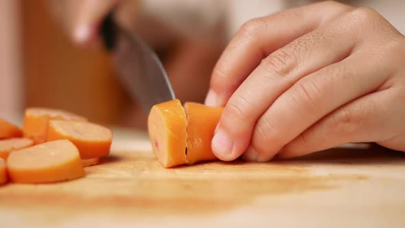 Close up of a knife cuts the sausage into small pieces.