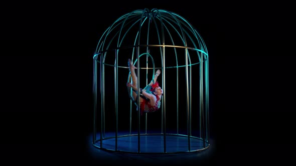 Artist on the Gymnastic Hoop Performs Tricks in a Cage on the Stage in the Dark