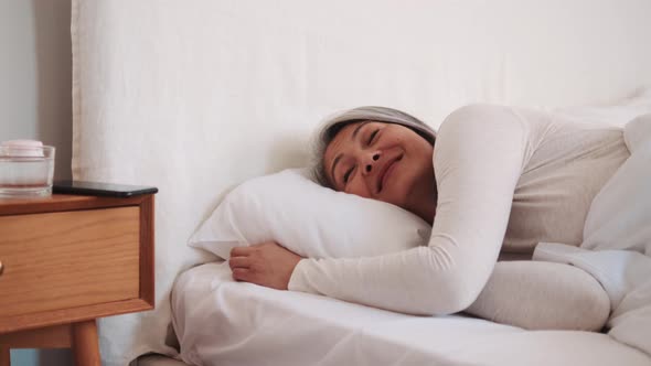 Laughing Asian woman wake up and looking at the phone