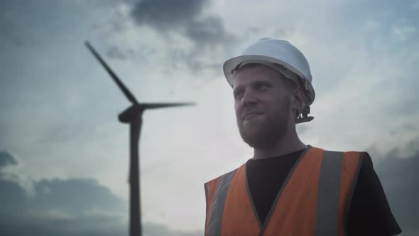 PORTRAIT Young Man with a Beard in a White Protective Helmet and a Vest Shows Like Thumb Up Approves