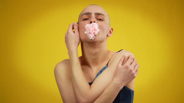 Portrait of Young Man in Dress Holding Flower in Mouth Hugging Himself Looking at Camera