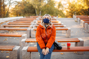 Woman in mask and outerwear in park