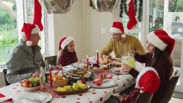 Happy caucasian multi generation family wearing santa hats, having christmas meal