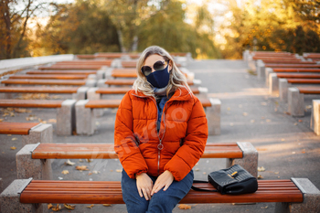 Woman in mask and outerwear in park