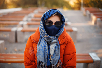 Woman in mask and outerwear in park