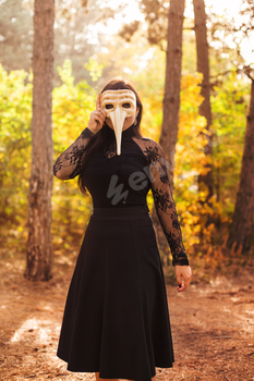 Woman in carnival mask in forest